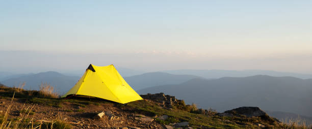 istock Panoramic view on yellow tent in mountains 2165516024