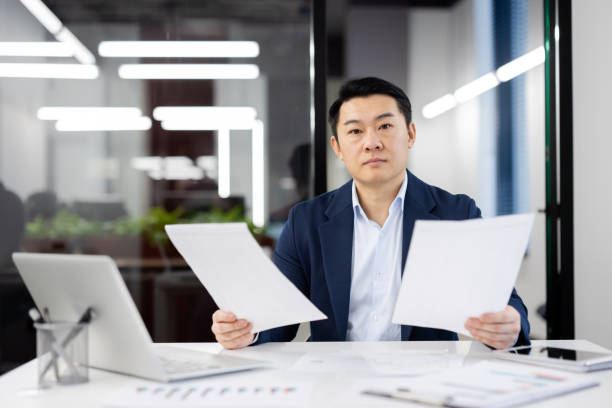 istock Asian businessman reviewing documents in modern office 2165517832