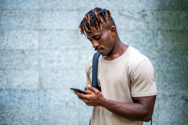 istock Smiling Black Man Engaged with Smartphone Outdoors 2165519223
