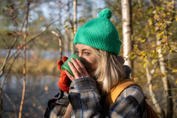istock Contented middle aged Scandinavian woman drinks hot tea while walks in eco forest park on fresh air. 2165520615