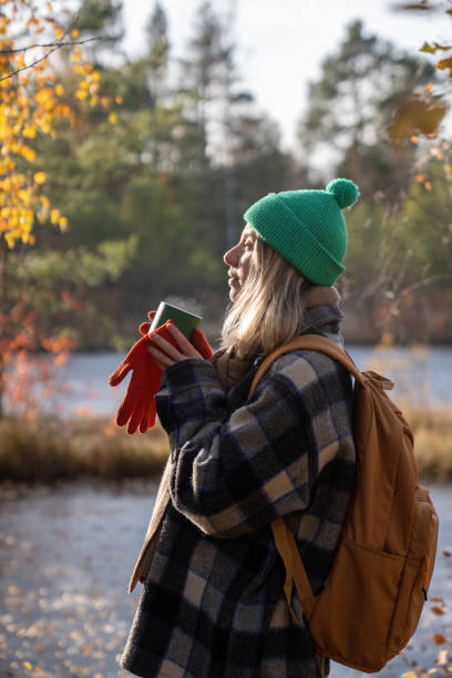 istock Relaxed woman standing while resting after hiking in pine forest, drinking hot tea, warming hands 2165520621
