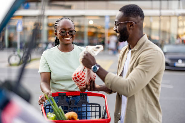 istock Smiling Black Couple Unloading Shopping Basket at Car 2165522187