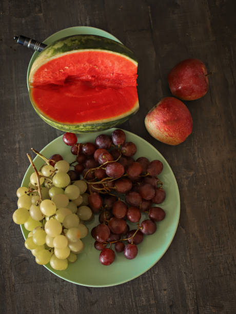 Watermelon, white and dark grapes, two apples on wooden background