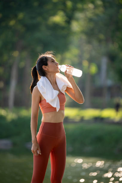 istock A woman is drinking water while wearing a white towel 2165527829