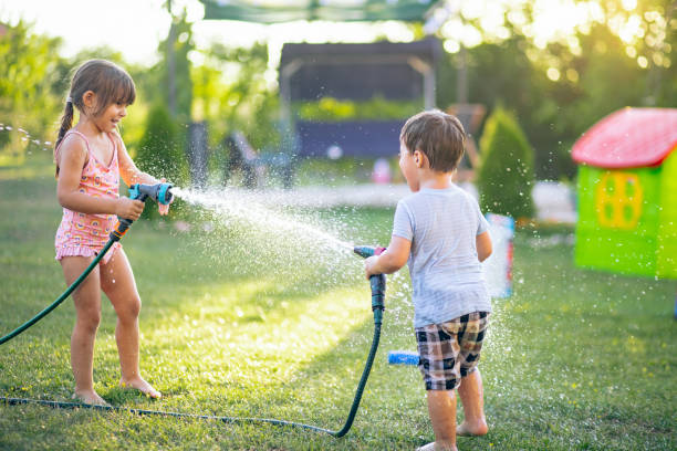 istock Two playful kids having fun while splashing water with garden hose 2165528194