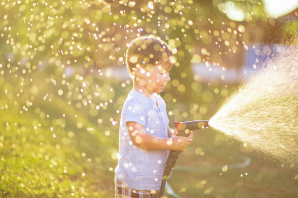 istock Little boy playing with water hose in garden 2165528382