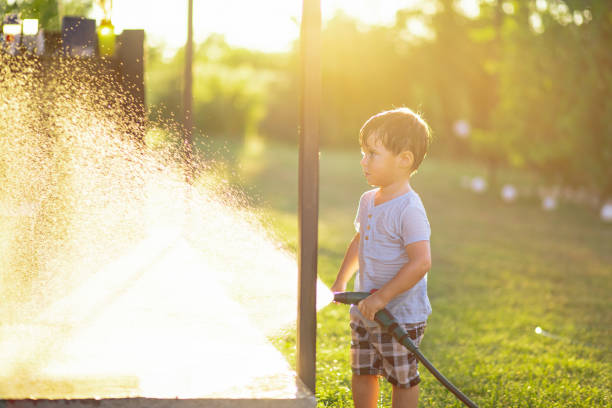 Little boy playing with water hose in garden