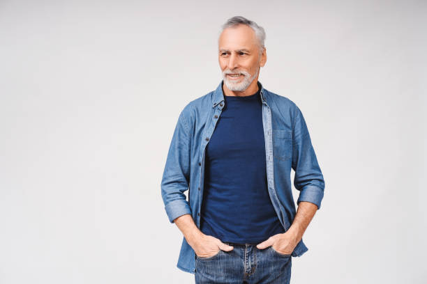 istock Smiling mature grey haired man holding hands in pockets against over white background 2165528538