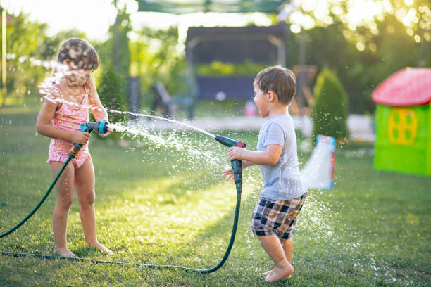 istock Two playful kids having fun while splashing water with garden hose 2165528779