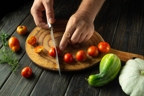 istock A cook prepares a vegetable lunch on the kitchen table. Slicing cherry tomatoes before cooking. Tomato diet menu 2165529498