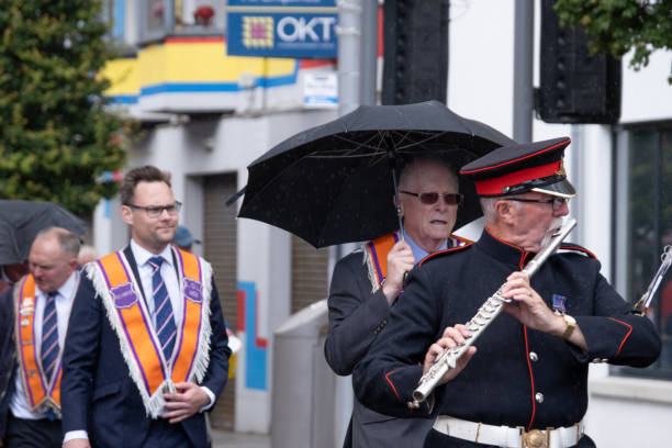 Ballymena, UK - June 25th 2022: Umbrellas out as brief rain shower falls on Broadway during annual Orange Order mini-Twelfth parade.