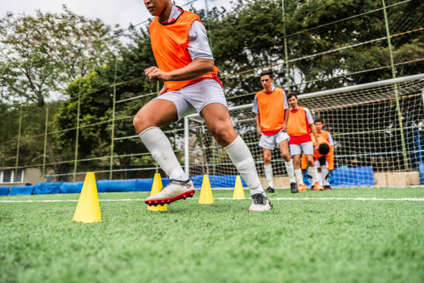 Children practicing soccer with training cones on green grass playground
