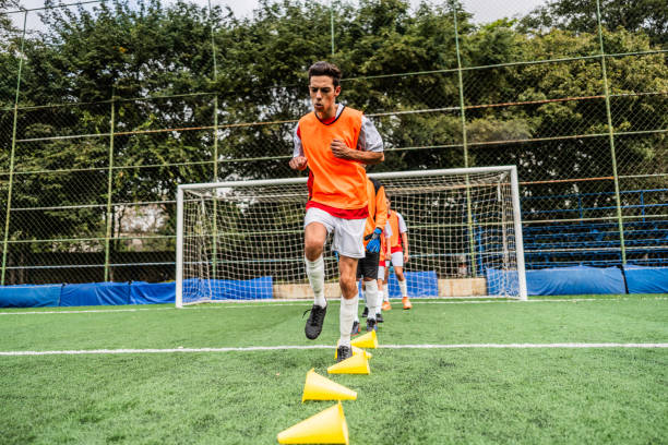 A series of bright and colorful training cones lined up perfectly on a vibrant green soccer field, serving as excellent tools for various drills and exercises aimed at skill development