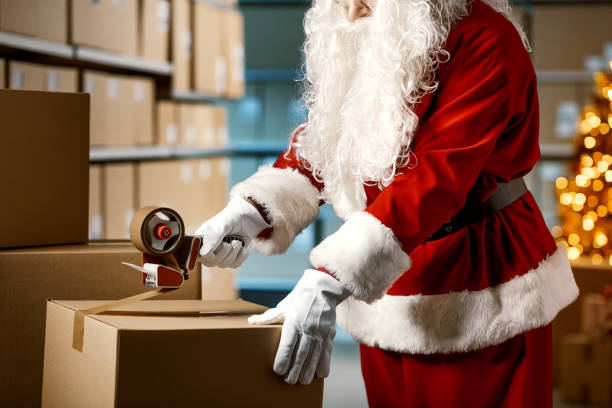 Santa Claus taping a delivery box at the warehouse