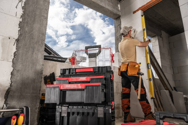 istock Construction Worker Measuring Wall Inside Renovating Building on a Partly Cloudy Day 2165546786