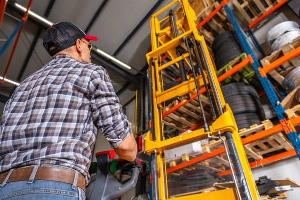 istock Warehouse Worker Using Forklift to Move Tires in Storage Area 2165549214