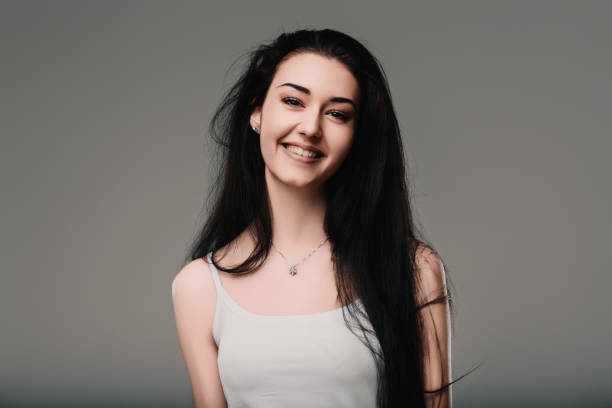 istock Young woman smiling and thinking on gray background 2165557070