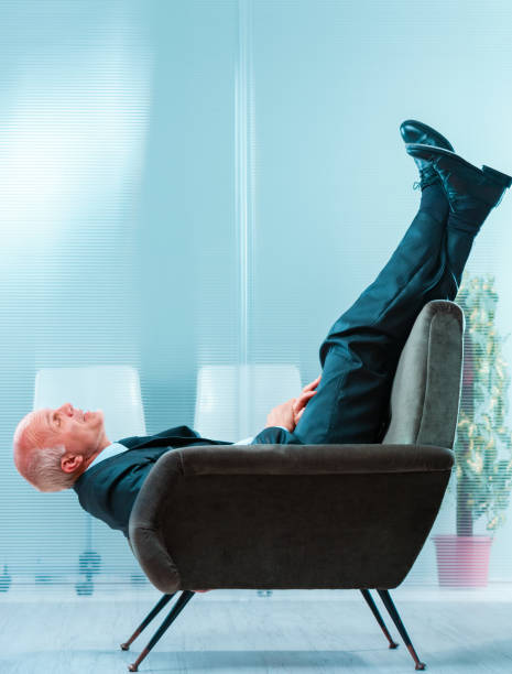 Relaxed young man talking on mobile phone at work with feet on desk