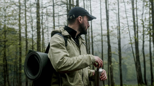istock Traveler hiker man with backpack walking, drinking water from a water flask in forest. Hiking, weekend activity, travel concept 2165564521