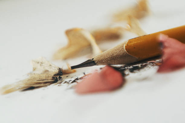 Several black pencils are neatly arranged in a row inside a silver metal container. The pencils are uniform in shape and size, creating a visually appealing pattern.
