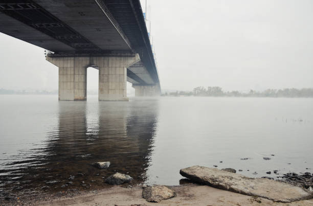 Perspective view of the bridge from a bank of the river. Bridge over a river - low visibility on October morning.