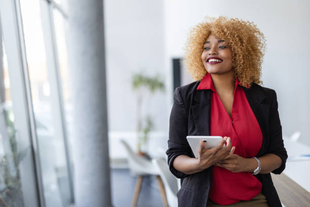 istock Joyful Woman Holding Tablet Office Background Smiling 2165570157