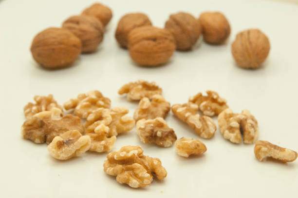 Group of shelled and unshelled walnuts separated and scattered on white background