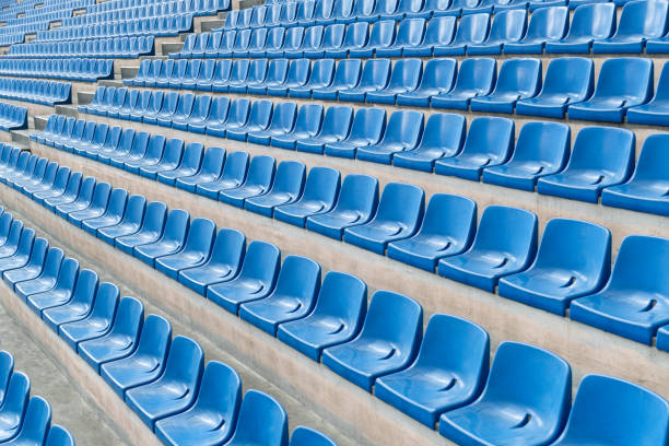 Empty blue  seats in a soccer stadium, arranged in rows for sporting and musical events.