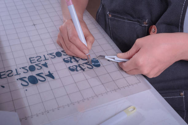 istock Young woman removes excess material with weeding tool, cutting plotter workplace. 2165580127