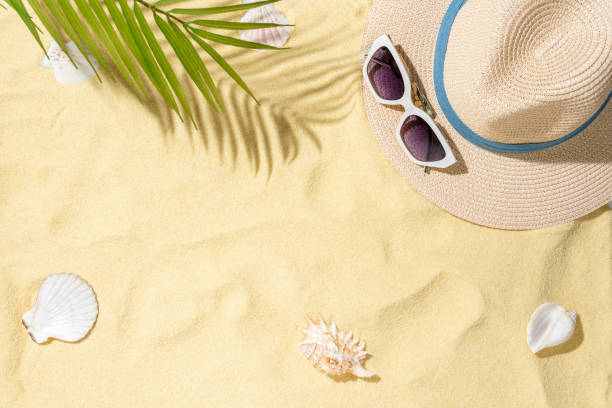 istock Sea sand with hat, sunglasses and shells. Top view with copy space. 2165586373