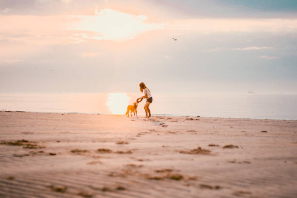 istock Young woman vacations at beach with pet dog 2165593271