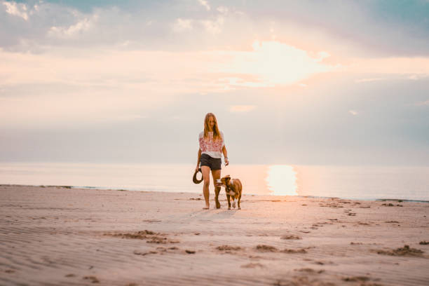 istock Young woman vacations at beach with pet dog 2165593314