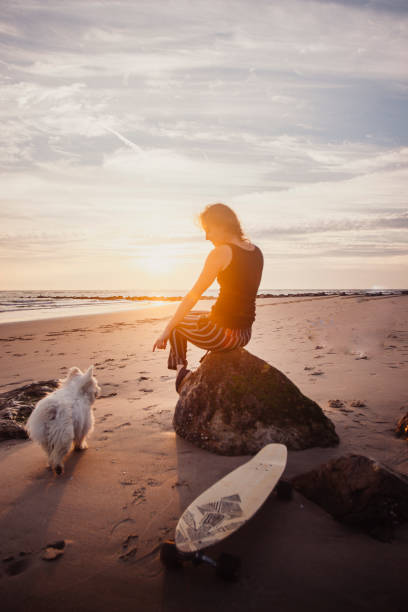 istock Young woman vacations at beach, with dog 2165596221