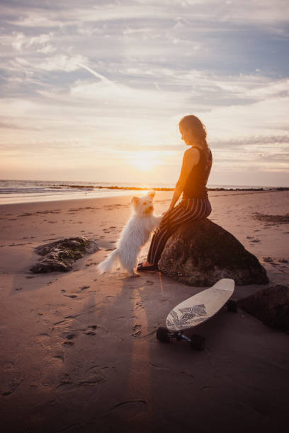 istock Young woman vacations at beach, with dog 2165596310