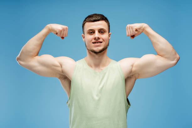 istock Handsome, smiling athletic man flexing muscles showing biceps isolated on blue background 2165597389