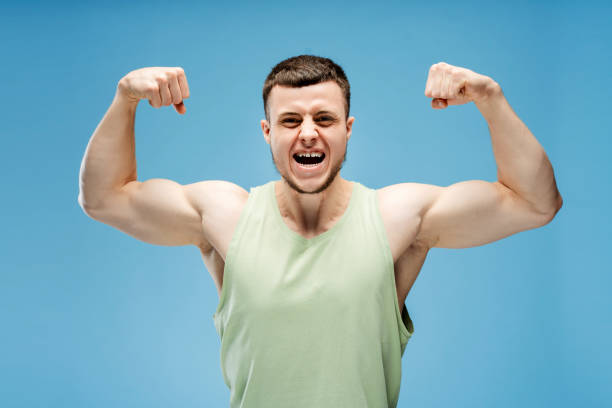 istock Young athletic man showing muscles and screaming standing isolated on blue background 2165597391