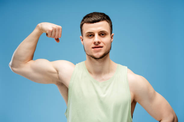 istock Smiling, young athletic man showing muscles isolated on blue background 2165597399