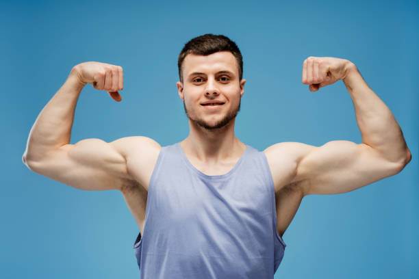istock Handsome athletic man showing muscles posing on blue background 2165597416