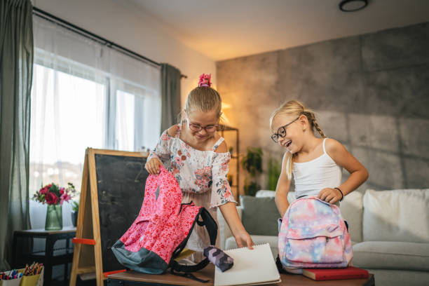 istock Two young school girls, friends pack book and notebook for school 2165598430