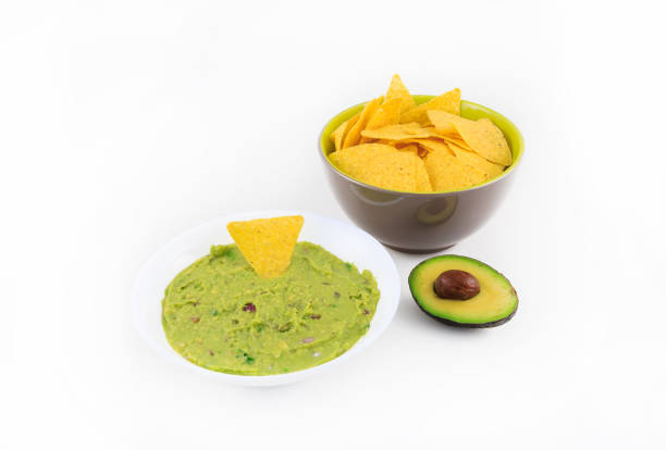Bowl of guacamole and nachos on white background.
