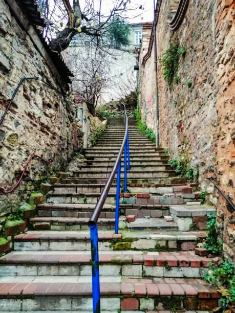 An old stone staircase with a blue handrail in the middle