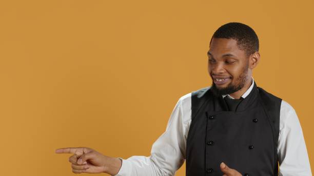 istock Waiter in professional uniform pointing at something to the left or right 2165603966
