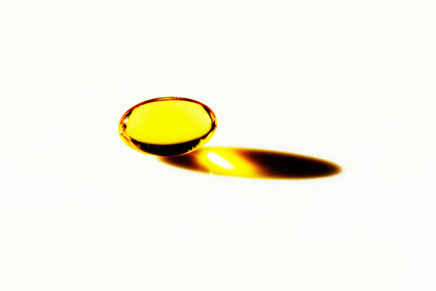 Yellow pill is sitting on a white background. The pill is the main focus of the image. Omega3 fatty acids