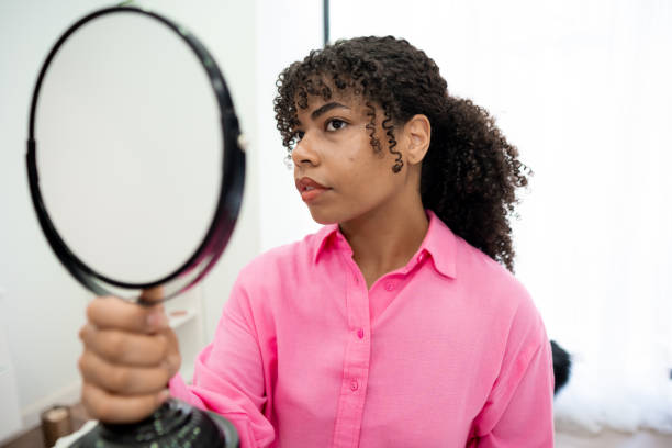 istock Patient looking herself on a hand mirror sitting on a beautician clinic 2165606552