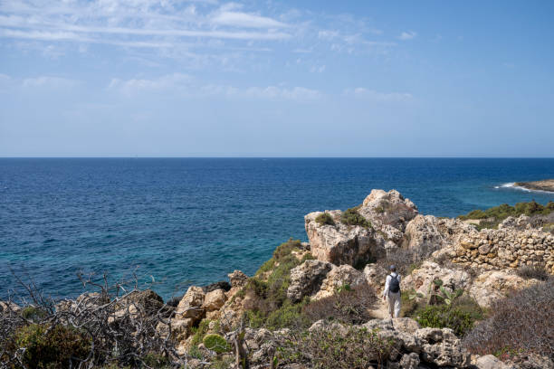 Woman explores rugged coastline, Gozo