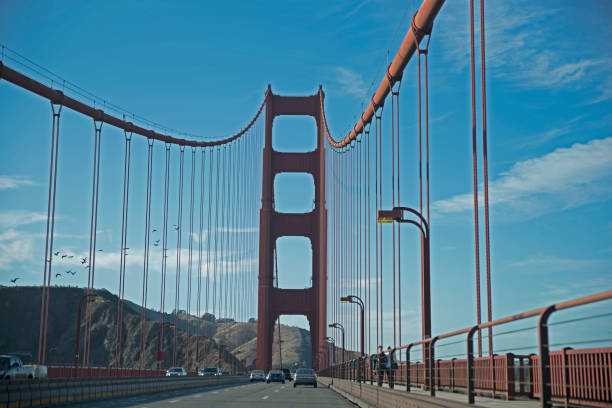 Close-up view of a red bridge's steel structure with rivets and industrial patterns. The image captures architectural elements and geometric lines, offering an abstract perspective.