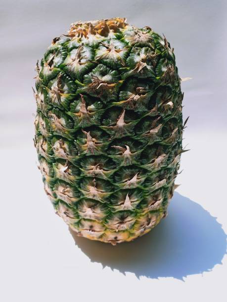 close-up of fresh pineapple fruit with green skin on a white background