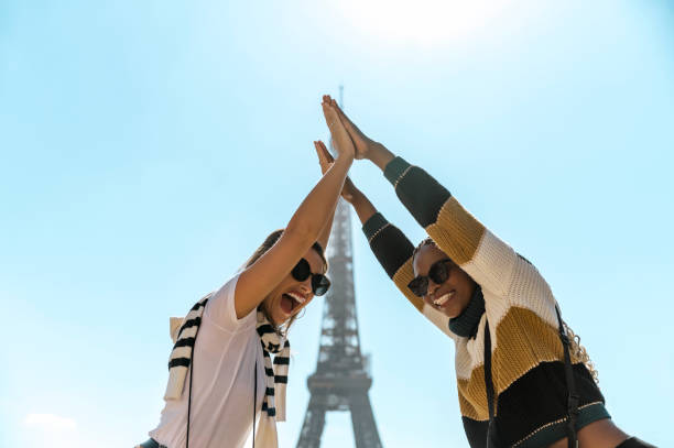 istock Low angle view of two excited multiethnic girlfriends doing high five with Eiffel Tower in background 2165626825