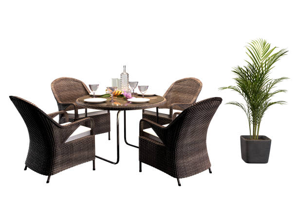 Four wicker chairs surrounding round table, potted palm tree.