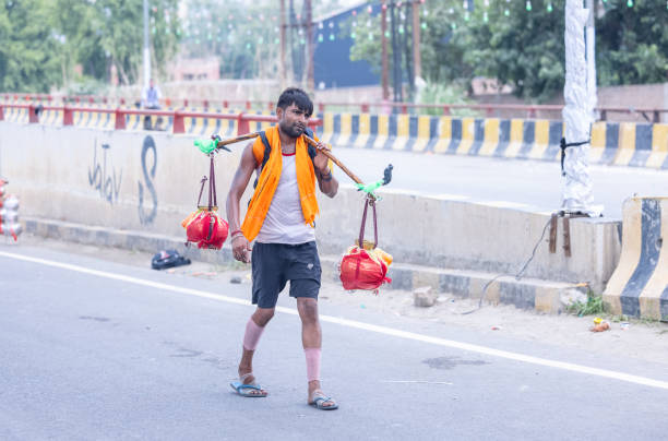 Ghaziabad, Uttar Pradesh, India - July 2024:  Portrait of hindu male pilgrims performing kanwar yatra barefoot during swan shivratri and carrying holy ganga water to worship hindu god shiv with rituals.